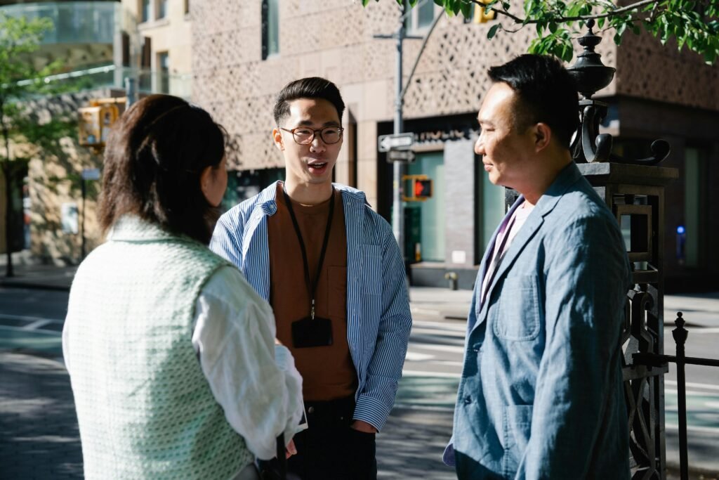 pexels-photo-7963807-7963807 Three professionals engaged in conversation outdoors in a city backdrop.